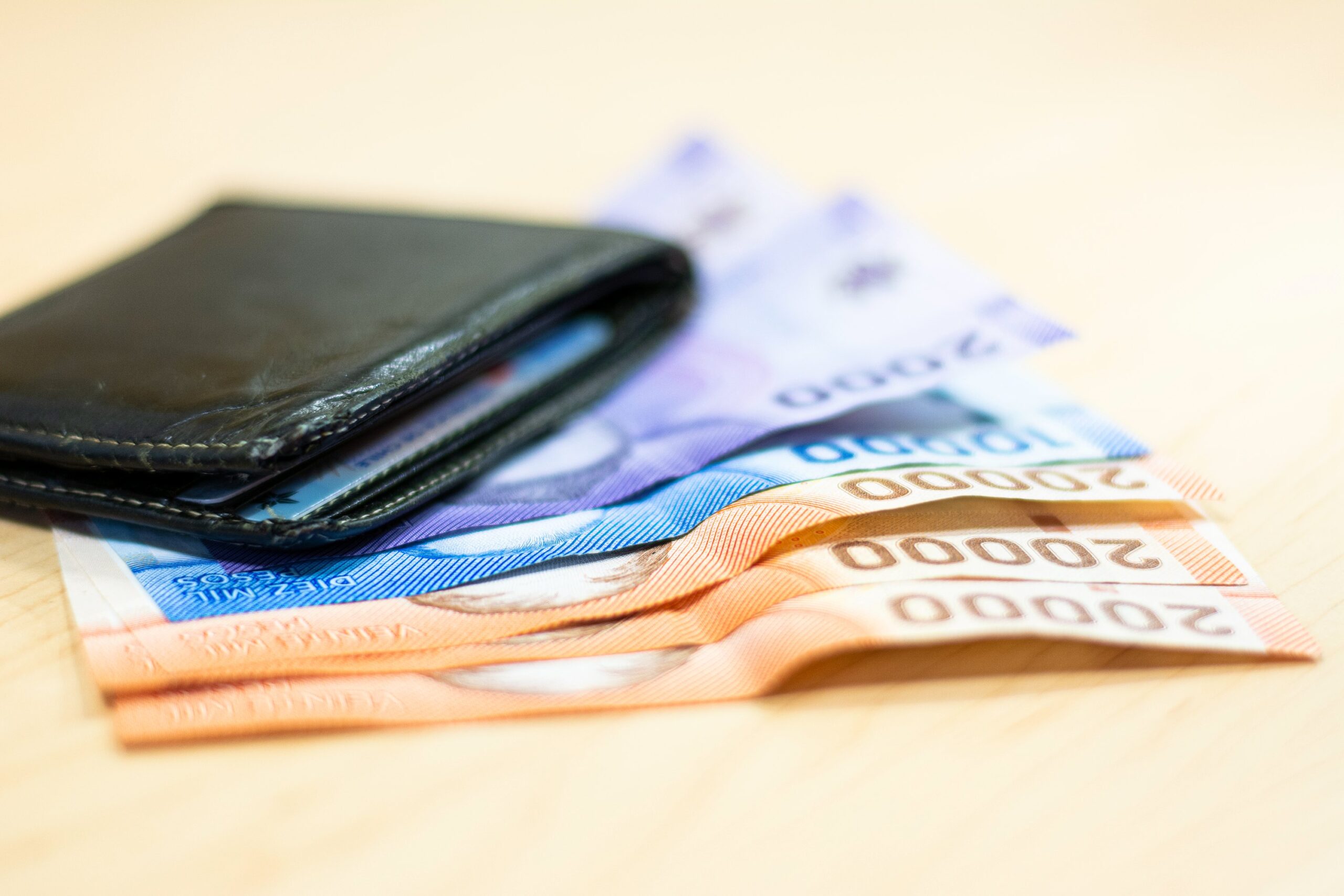 Billetera de cuero negro sobre billetes de pesos chilenos