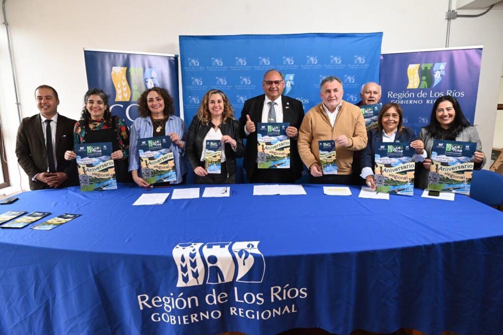 Autoridades del Gobierno Regional de Los Ríos mostrando folletos del programa del Aniversario Regional