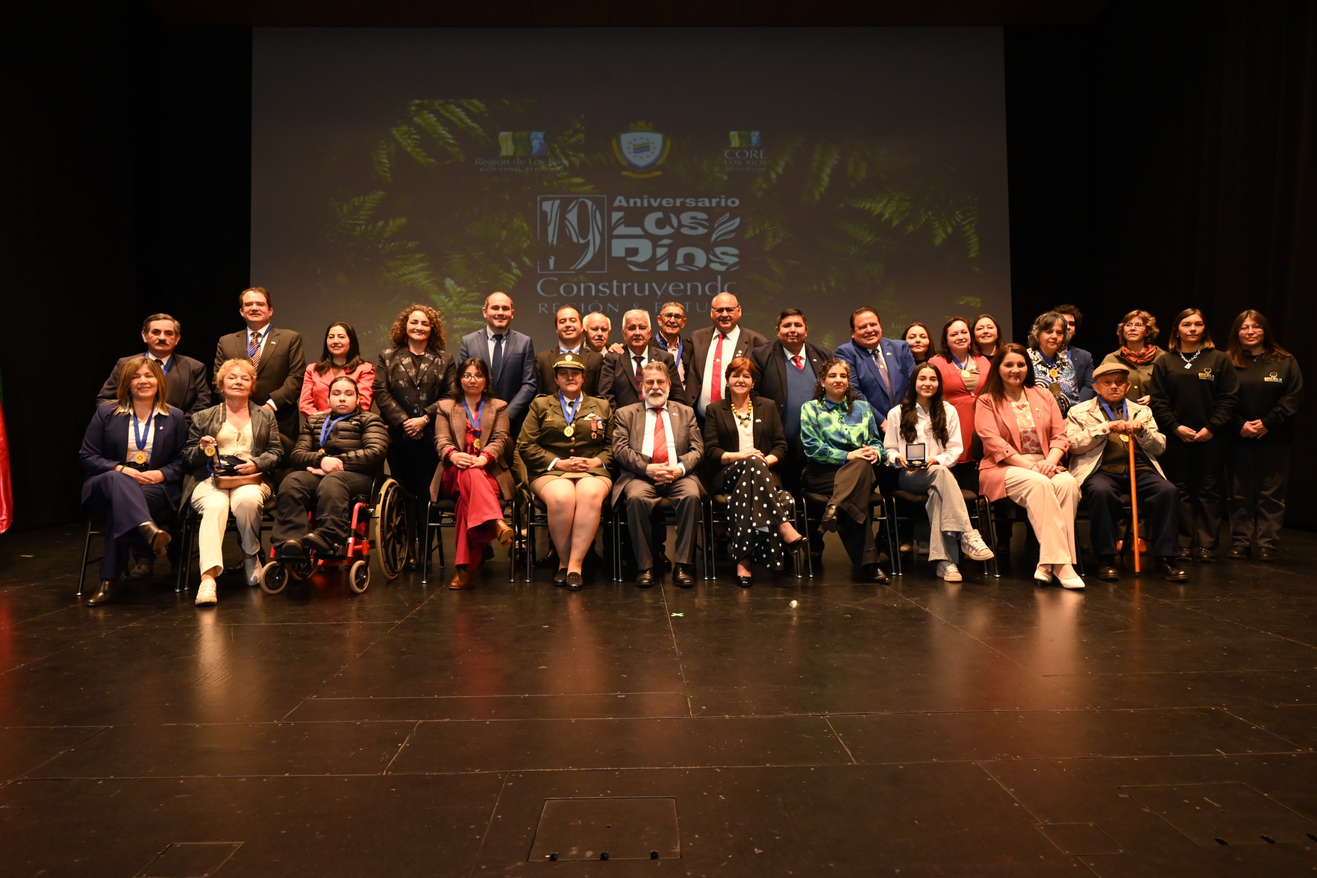 Autoridades y homenajeados posan en el escenario durante la celebración del 16.° aniversario de la Región de Los Ríos