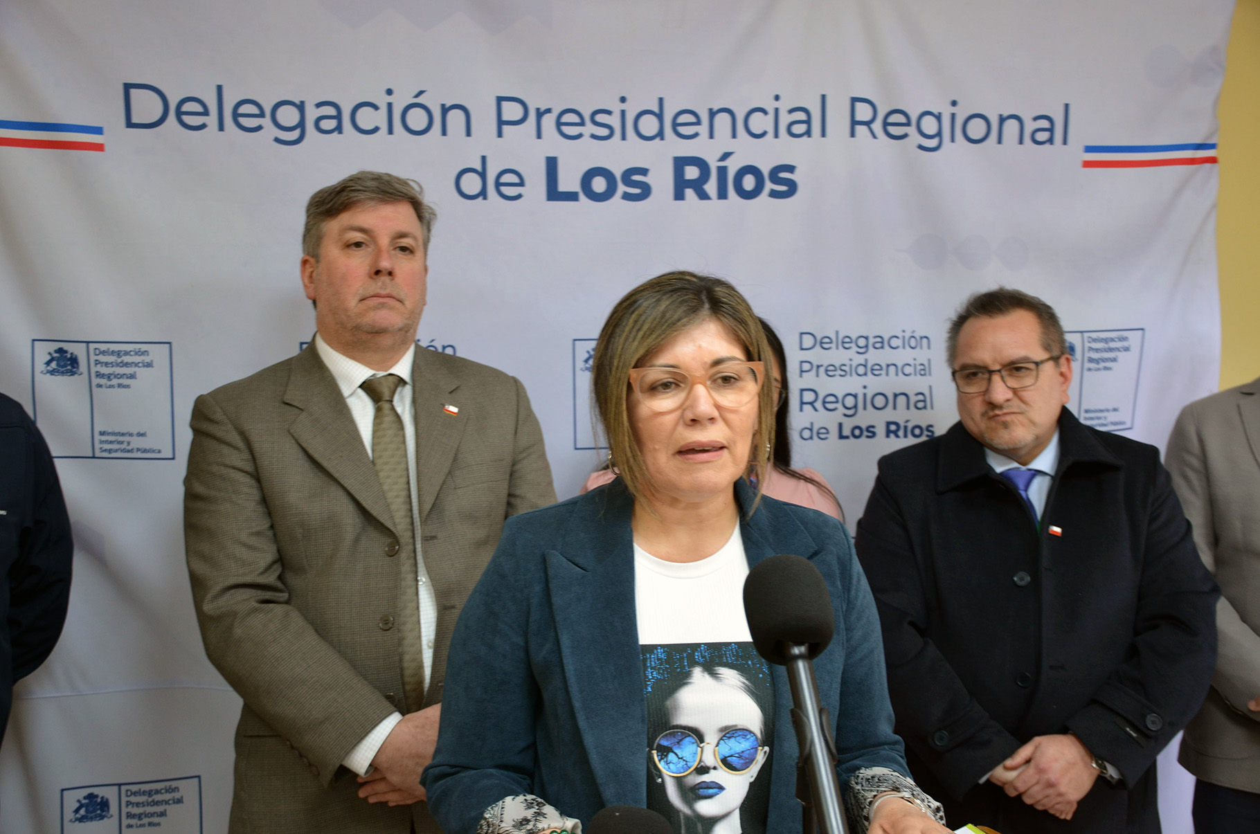 Una autoridad habla en un punto de prensa frente al telón de la Delegación Presidencial Regional de Los Ríos